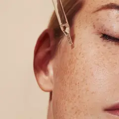 Kropla serum z pipety spada na piegowatą skórę. Dowiedz się, retinol co to i jak działa.