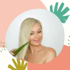 Blondynka z uśmiechem dotyka włosów liściem aloesu, który może być naturalnym żelem aloesowym na włosy.