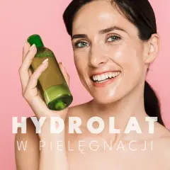 Uśmiechnięta kobieta trzyma buteleczkę z zielonym płynem. To jej ulubiony hydrolat do twarzy, który dodaje blasku.
