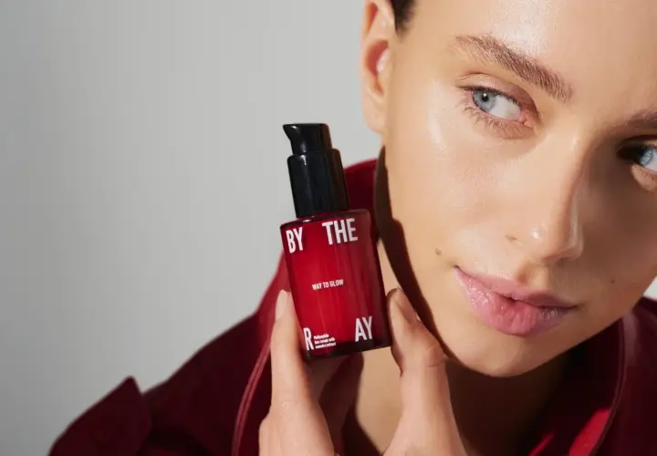 Kobieta z serum z peptydami w kosmetyce. Czerwona buteleczka z napisem "WAY TO GLOW" i "multipeptide face serum".