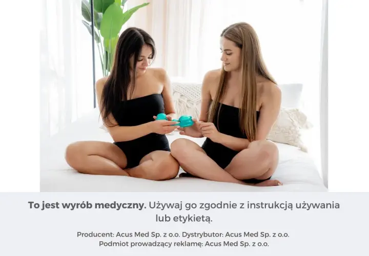 Dwie kobiety siedzą na łóżku, trzymając w dłoniach bańki chińskie. Jedna z nich pokazuje drugiej, jak wykonać masaż brzucha bańką chińską.