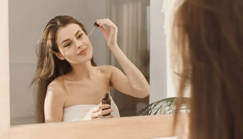 Kobieta aplikuje serum na twarz, zastanawiając się, czy niacynamid można łączyć z kwasem azelainowym.