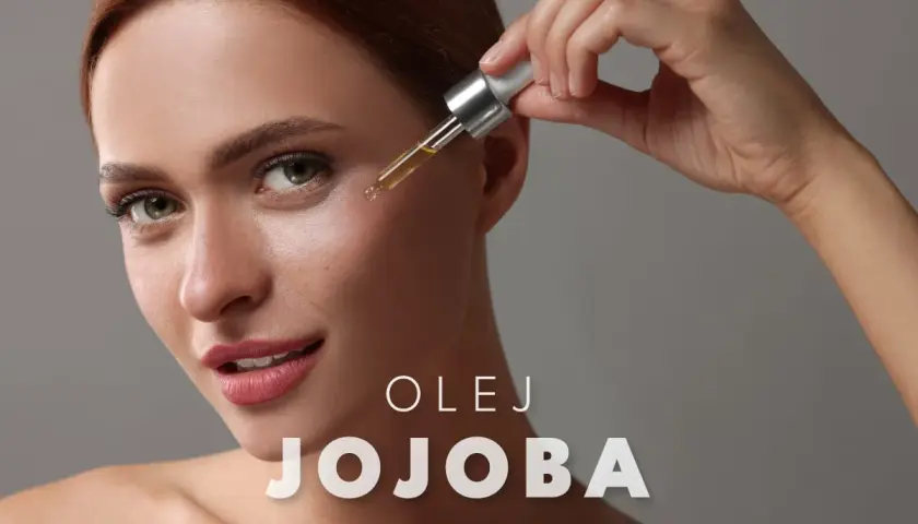 Kobieta aplikuje kroplę olejku jojoba na twarz. Delikatna pielęgnacja dla promiennej cery.