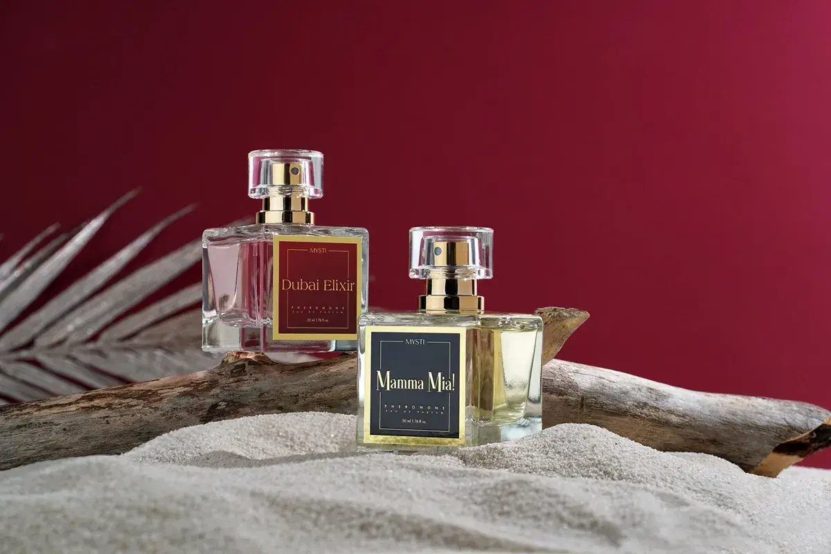 Dwa flakoniki perfum z feromonami na piasku. Czy perfumy z feromonami działają? Zobacz "Dubai Elixir" i "Mamma Mia!".