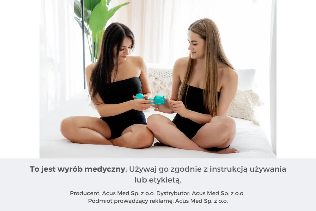 Dwie kobiety siedzą na łóżku, trzymając w dłoniach bańki chińskie. Jedna z nich pokazuje drugiej, jak wykonać masaż brzucha bańką chińską.
