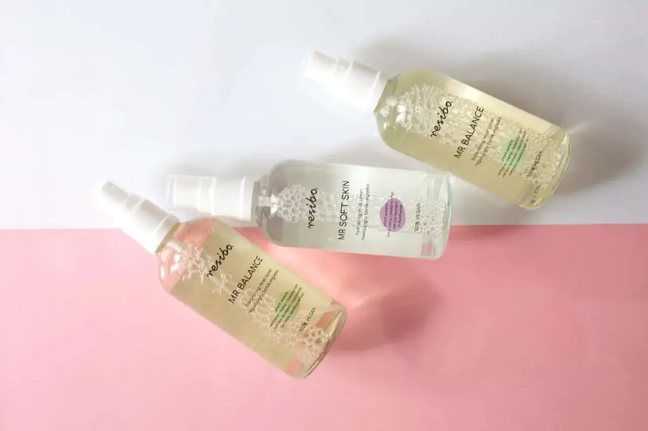 Trzy buteleczki hydrolat do twarzy Resibo: MR BALANCE i MR SOFT SKIN, na r&oacute;żowo-białym tle.